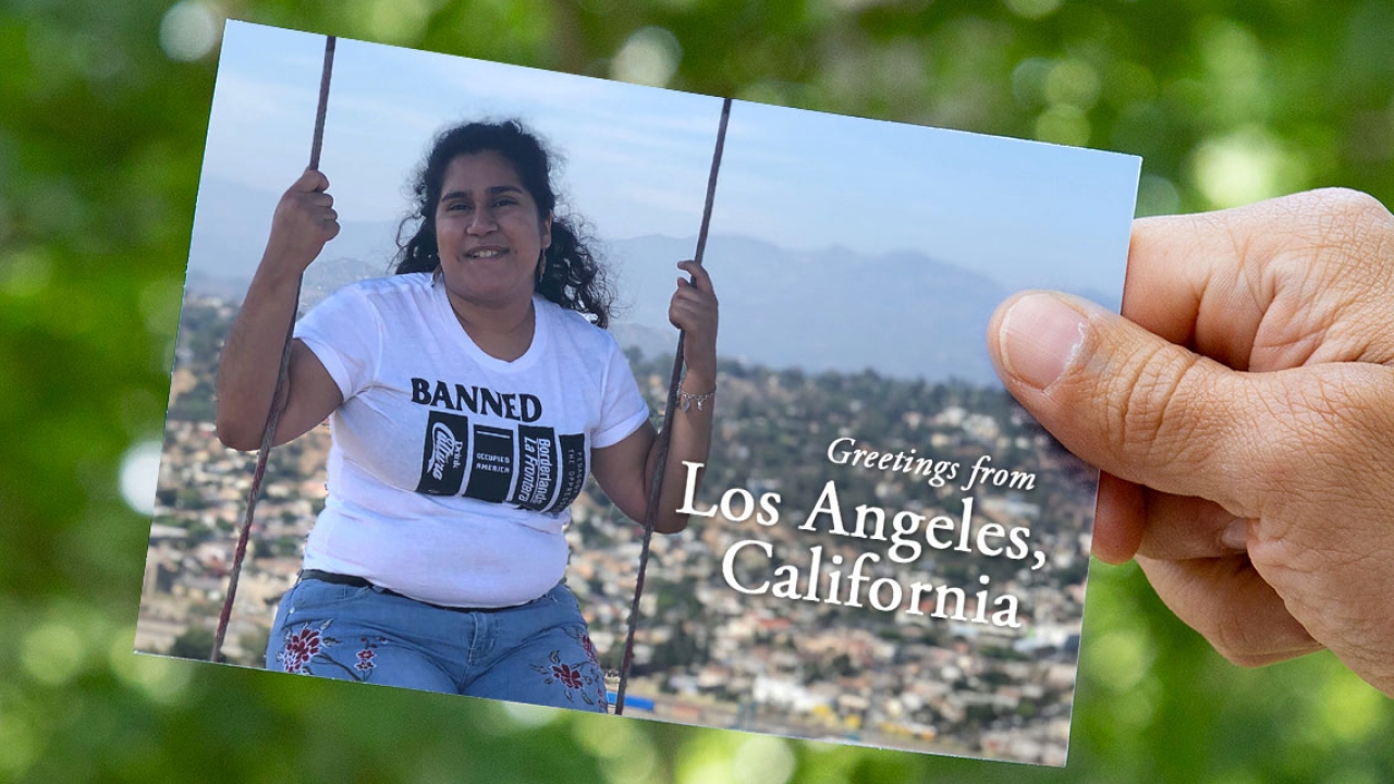On a postcard, a student sits on a swing that overlooks Los Angeles. 