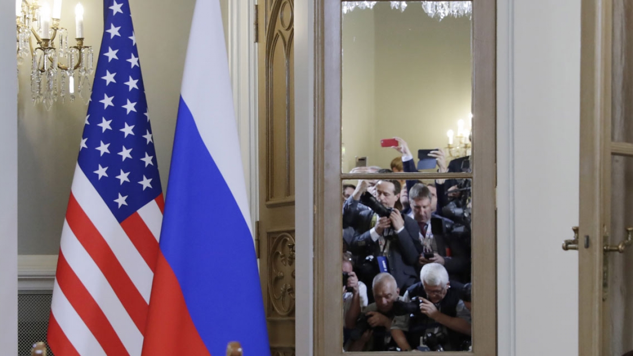 The American and Russian flags stand outside a conference room where members of the international press take photos.