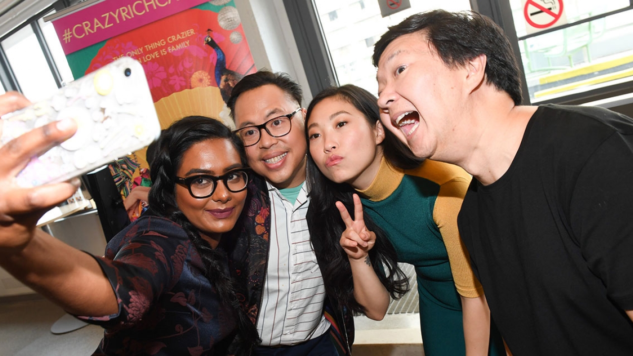The cast and crew of Crazy Rich Asians take a photo with a fan.