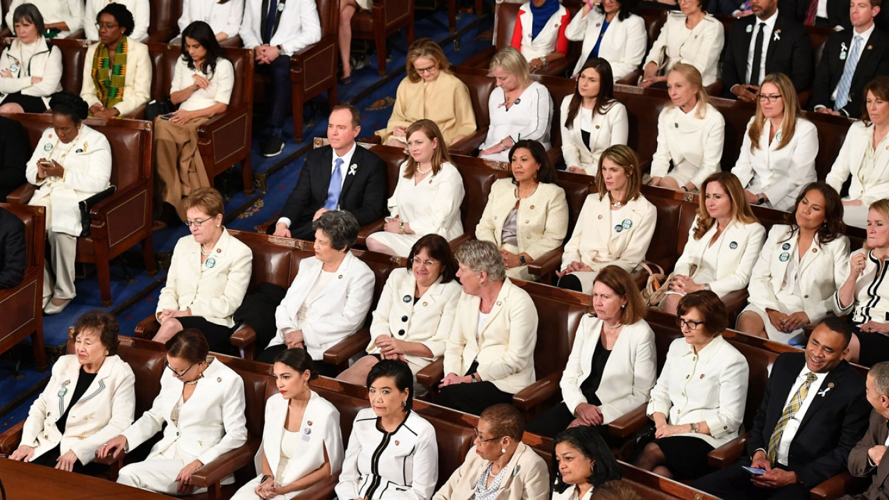 Women members of congress sit wearing white. 