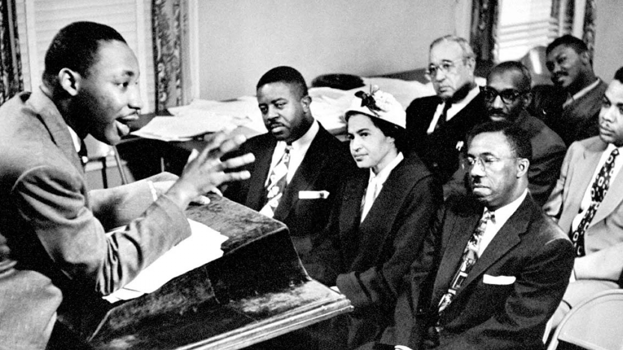 Martin Luther King talks to activists from a podium in a small room