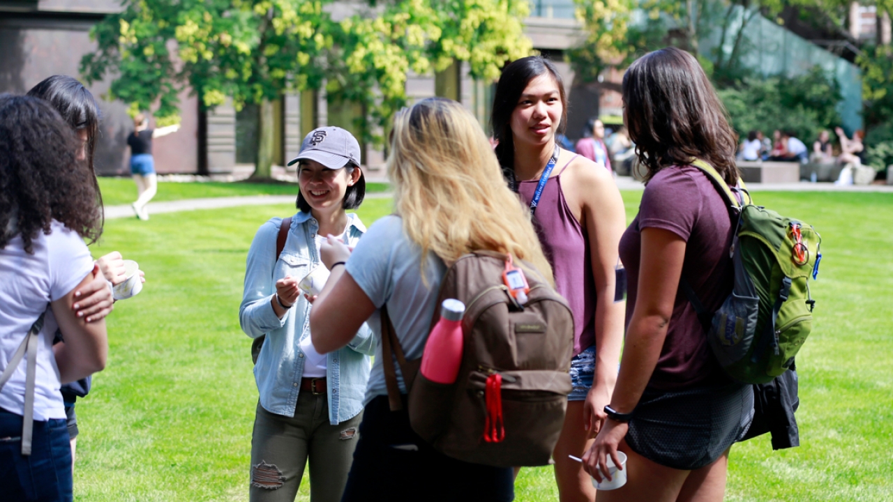 A group of student leaders stand outside at an ice cream social, talking.