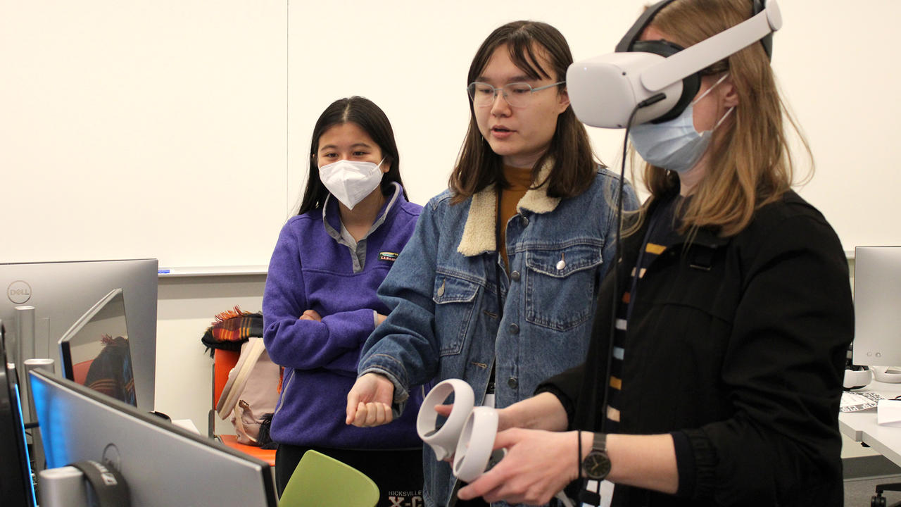 Rik Sampson ’23 (center) explains their virtual reality game to jury member Johanna Okerlund '14. 