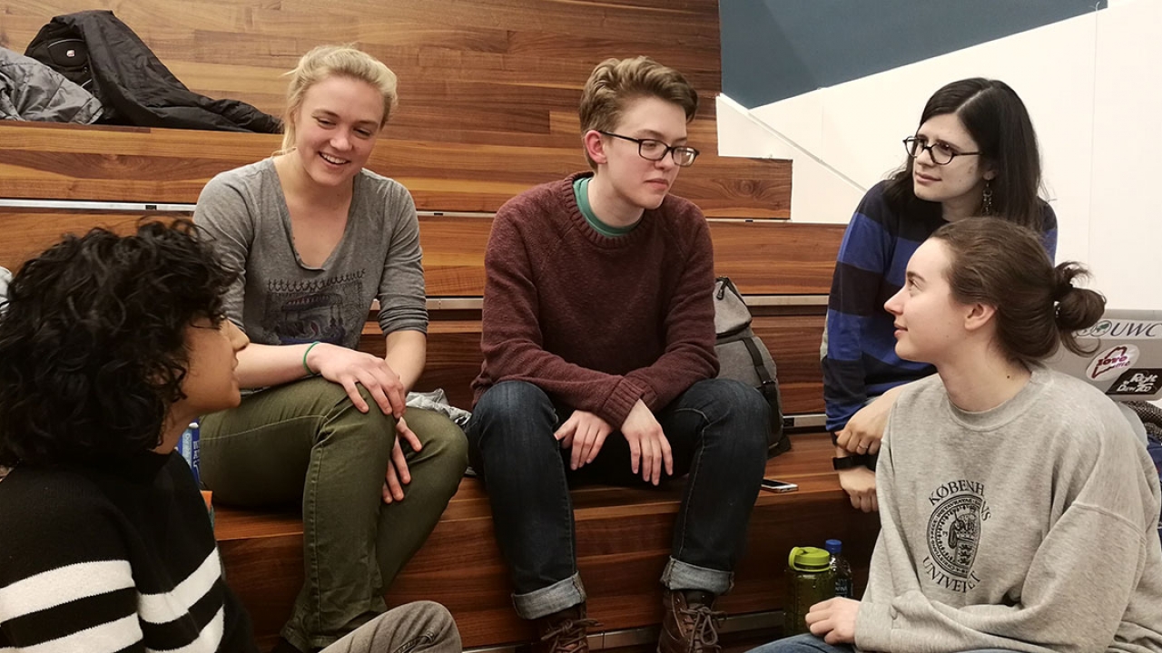 Five Wellesley students sit on bleachers discussing strategy at BOW Datafest