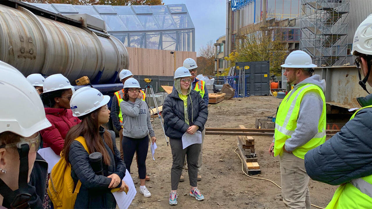 Students stand outside the science building wearing construction hats