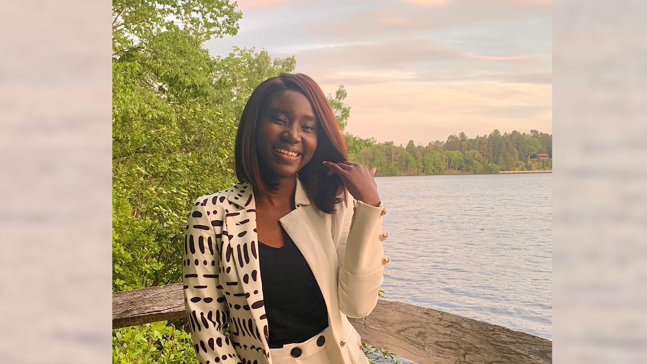 Adwoa Difie Antwi ’21 posing in front of Lake Waban with a sunset sky