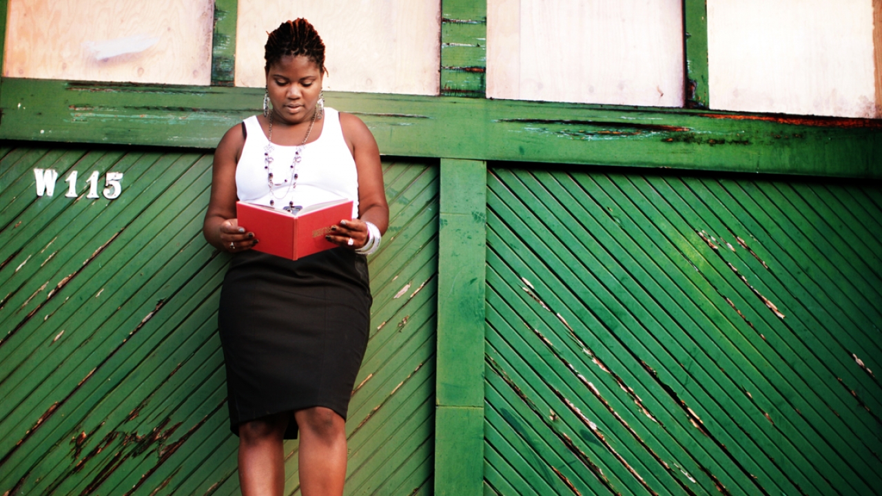 A woman stands against a green backdrop. 