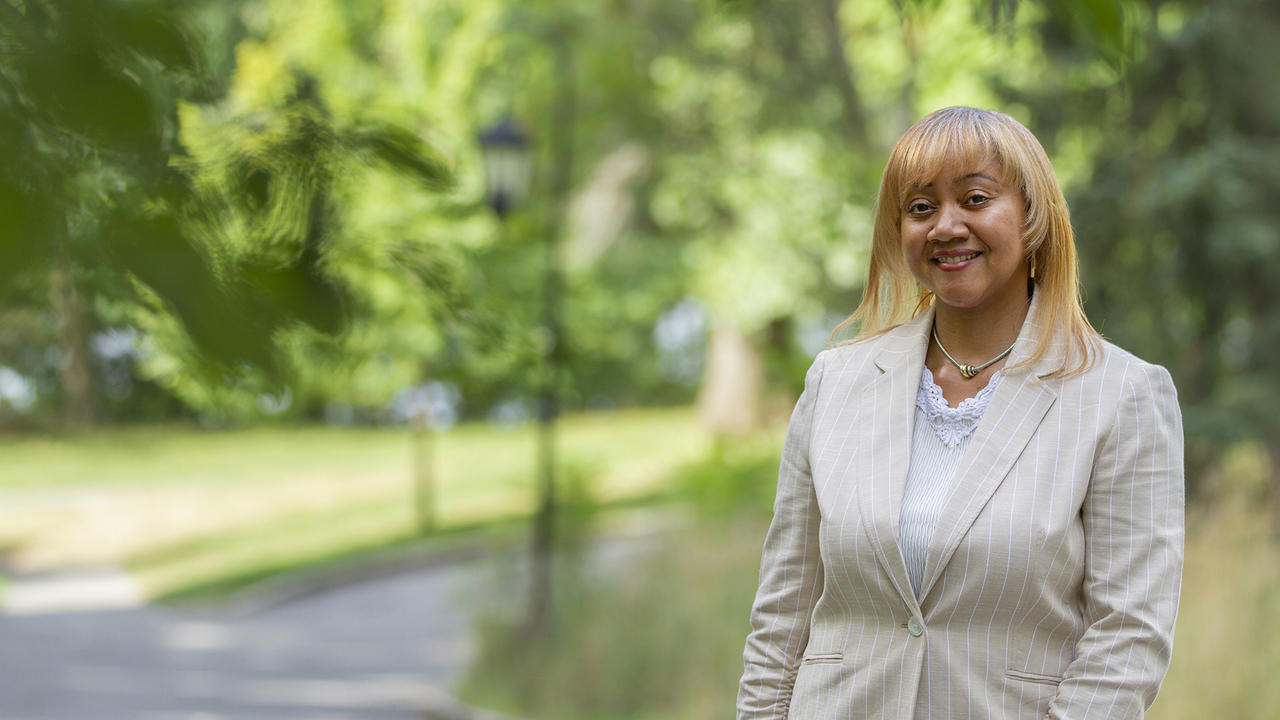 Jamie Motley smiles at the camera. Behind her is lush green campus.