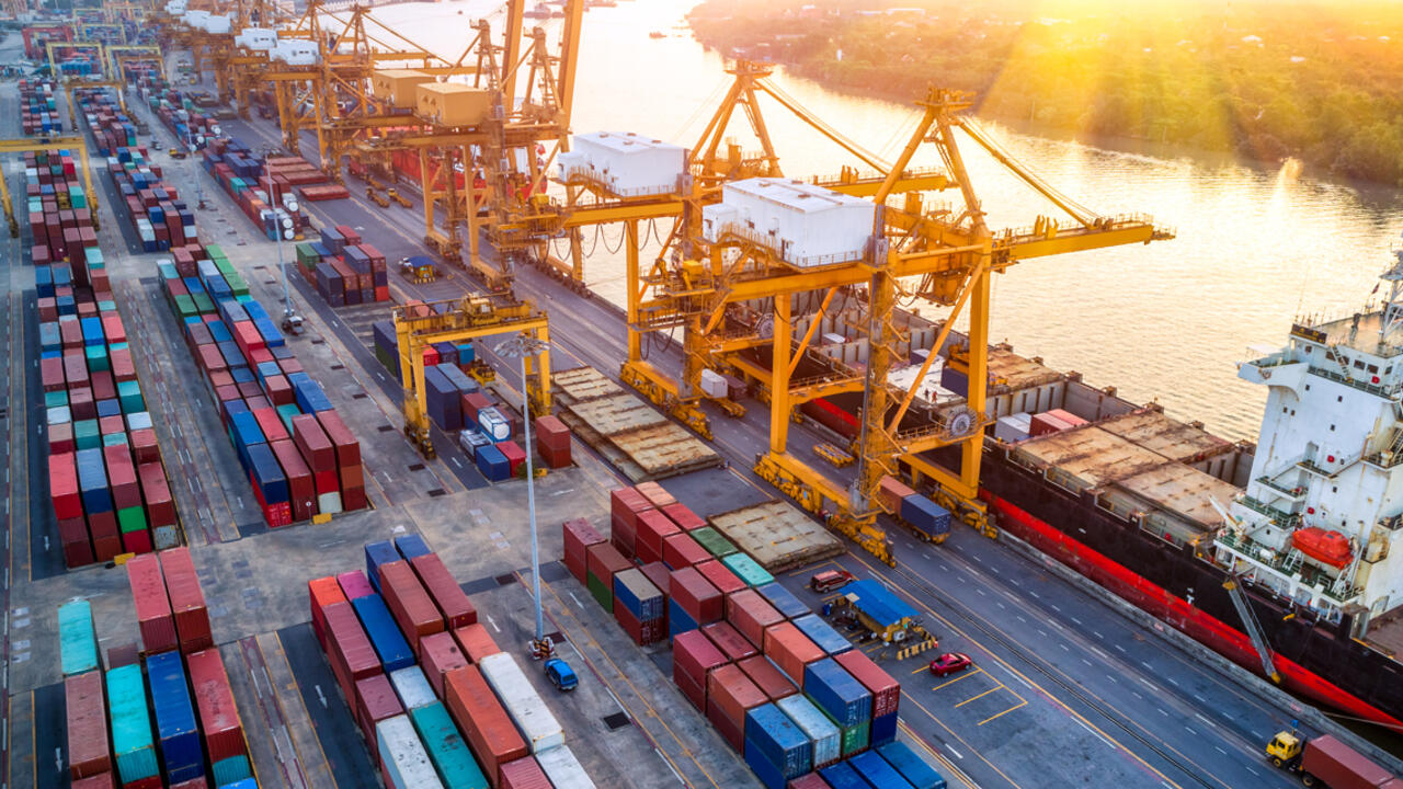 Logistics and transportation of Container Cargo ship with working crane bridge in shipyard at sunrise, 