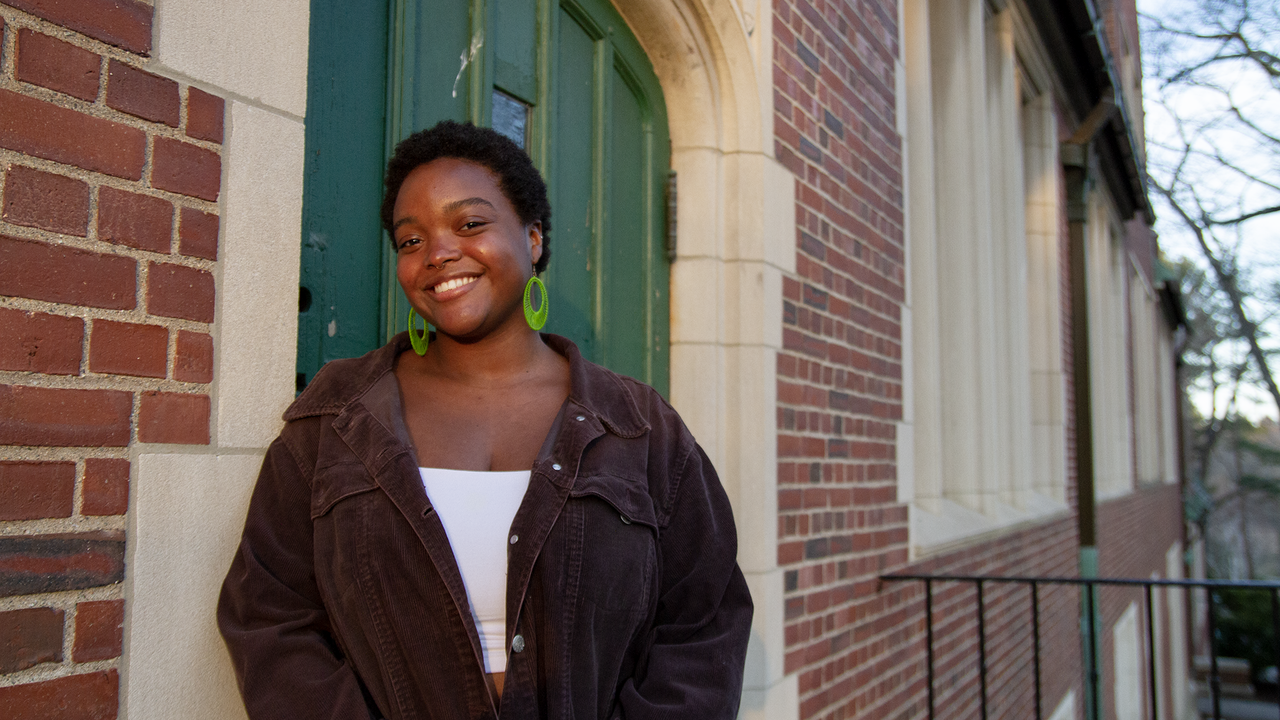 Kayla Bobb stands in front of a campus building and smiles at the camera.