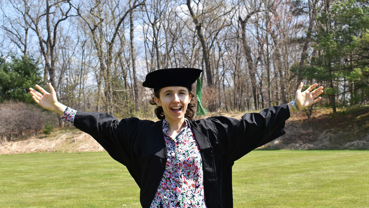 Liz Borecki ’21 wearing commencement robes standing on campus