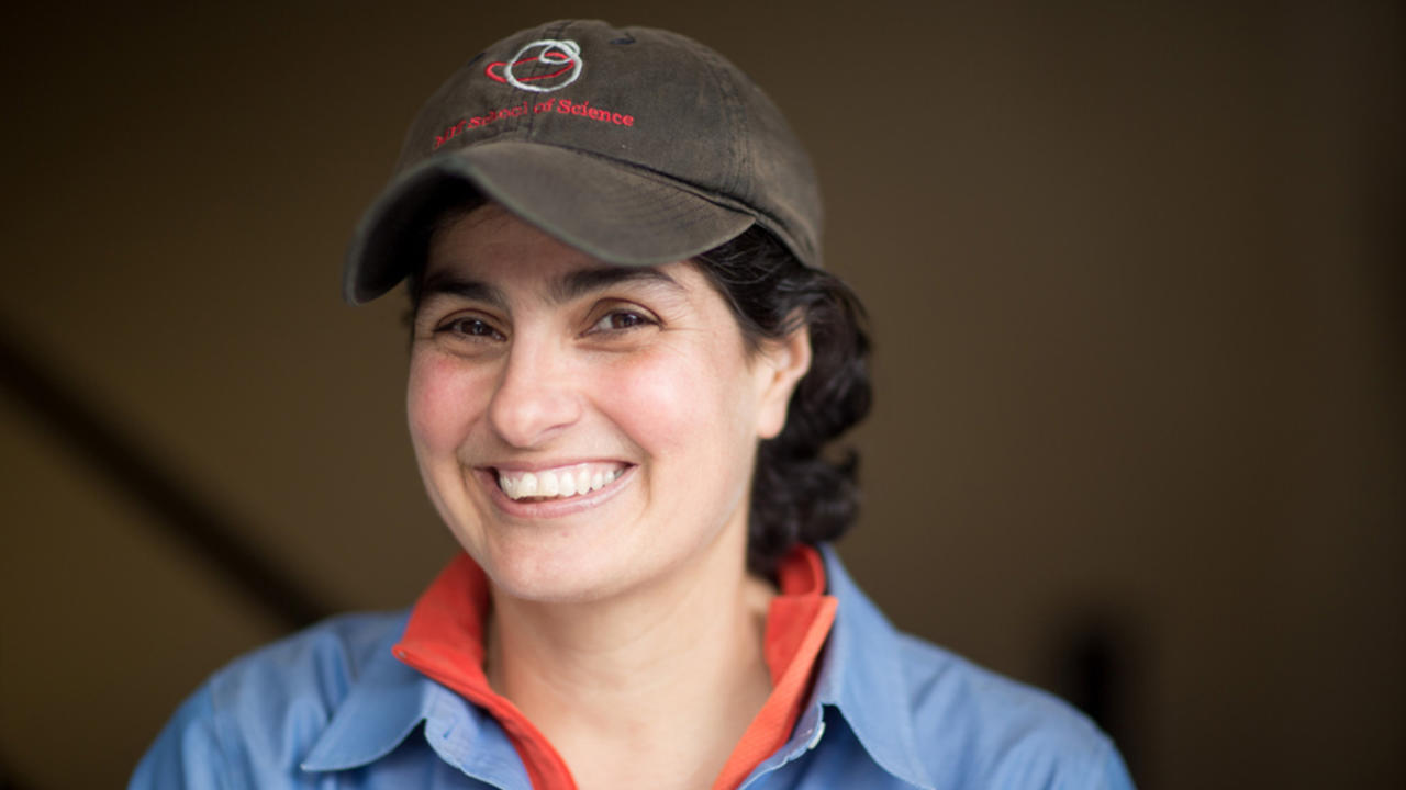 Portrait of alum Nergis Mavalvala wearing a cap and smiling at the camera.