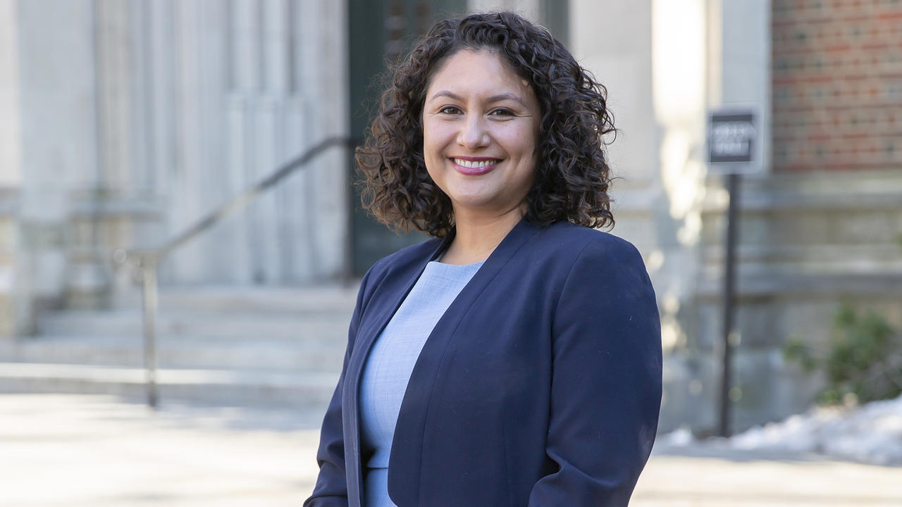 A portrait of Professor Natali Valdez, shown from waist up. She wears a dark blue blazer and is smiling at camera.