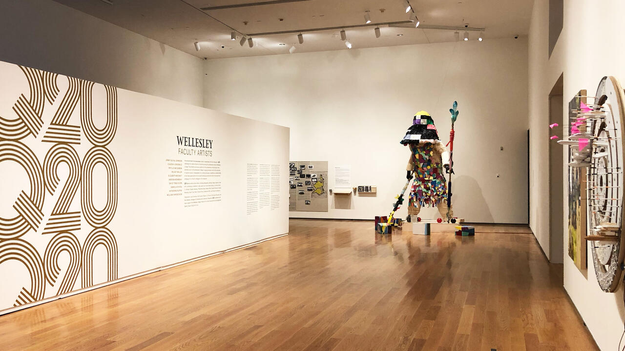 In the Davis Museum. a figure like sculpture stands in a corner.