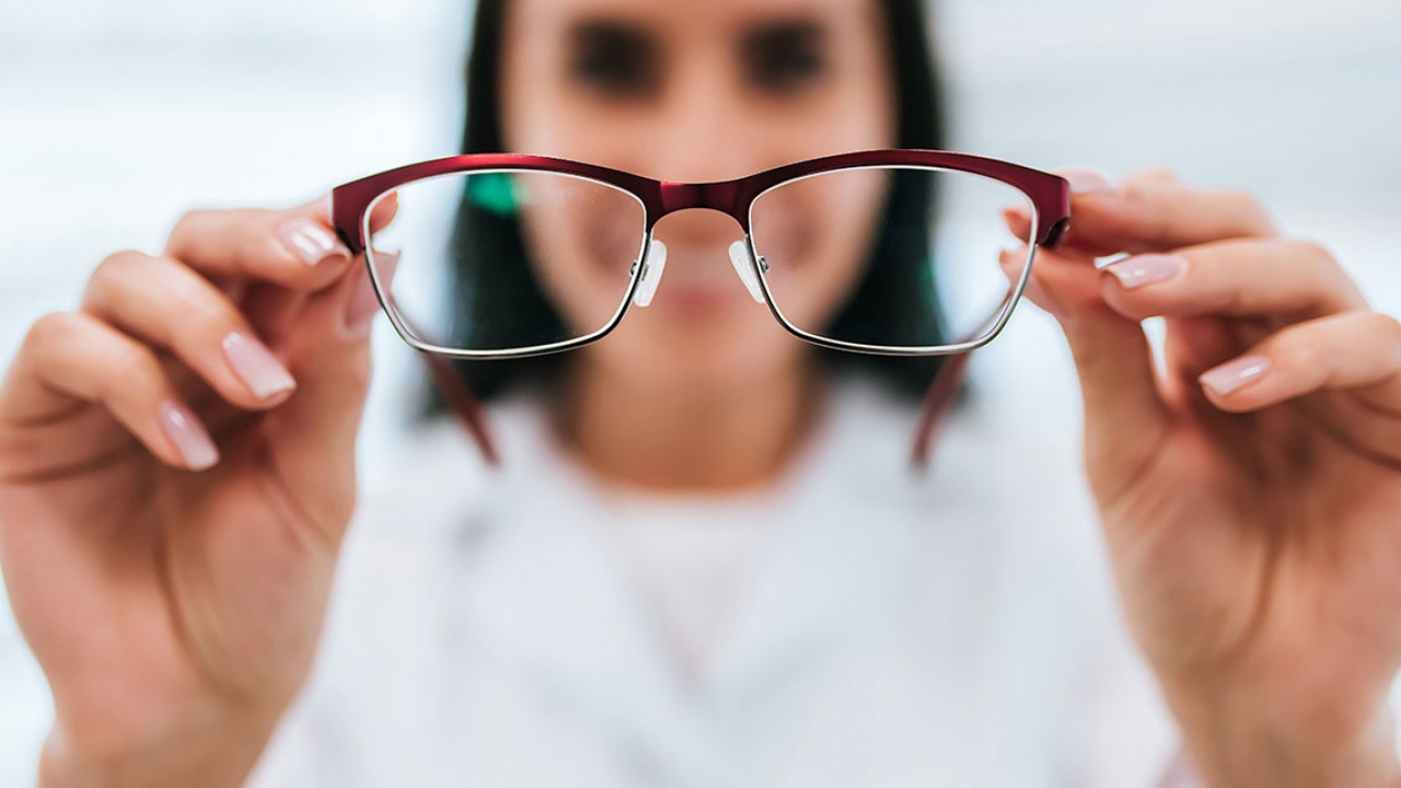 A woman holds eye glasses.