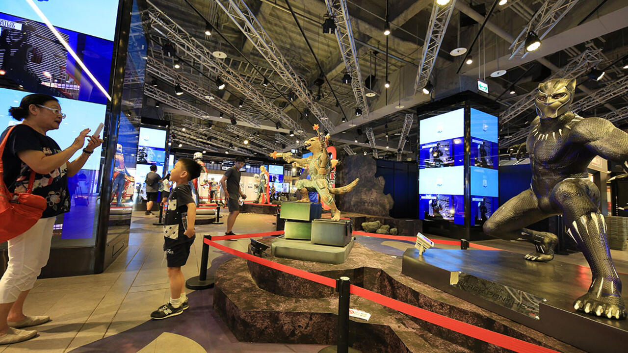 A mother and son look at an exhibit about Black Panther 