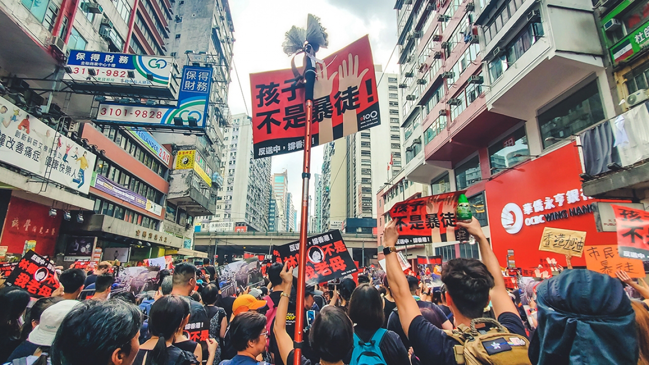 Protestors stand in a street in Hong Kong with signs. 
