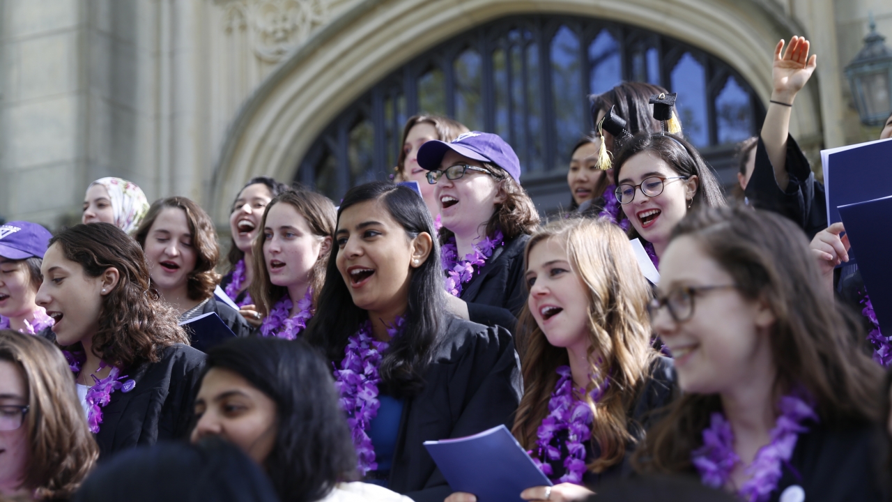 Members of the Class of 2018 sing on the steps of Houghton Chapel at Wellesley College.