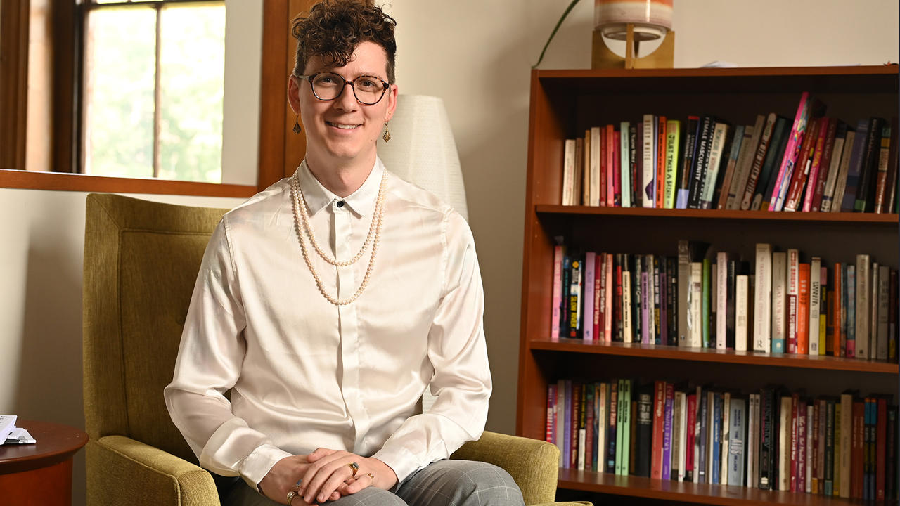 Todd Nordgren sits facing the camera, a bookshelf to his left.