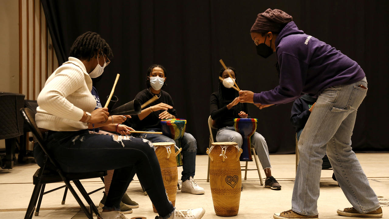 Kera Washington demonstrates drumming to students in Yanvalou.