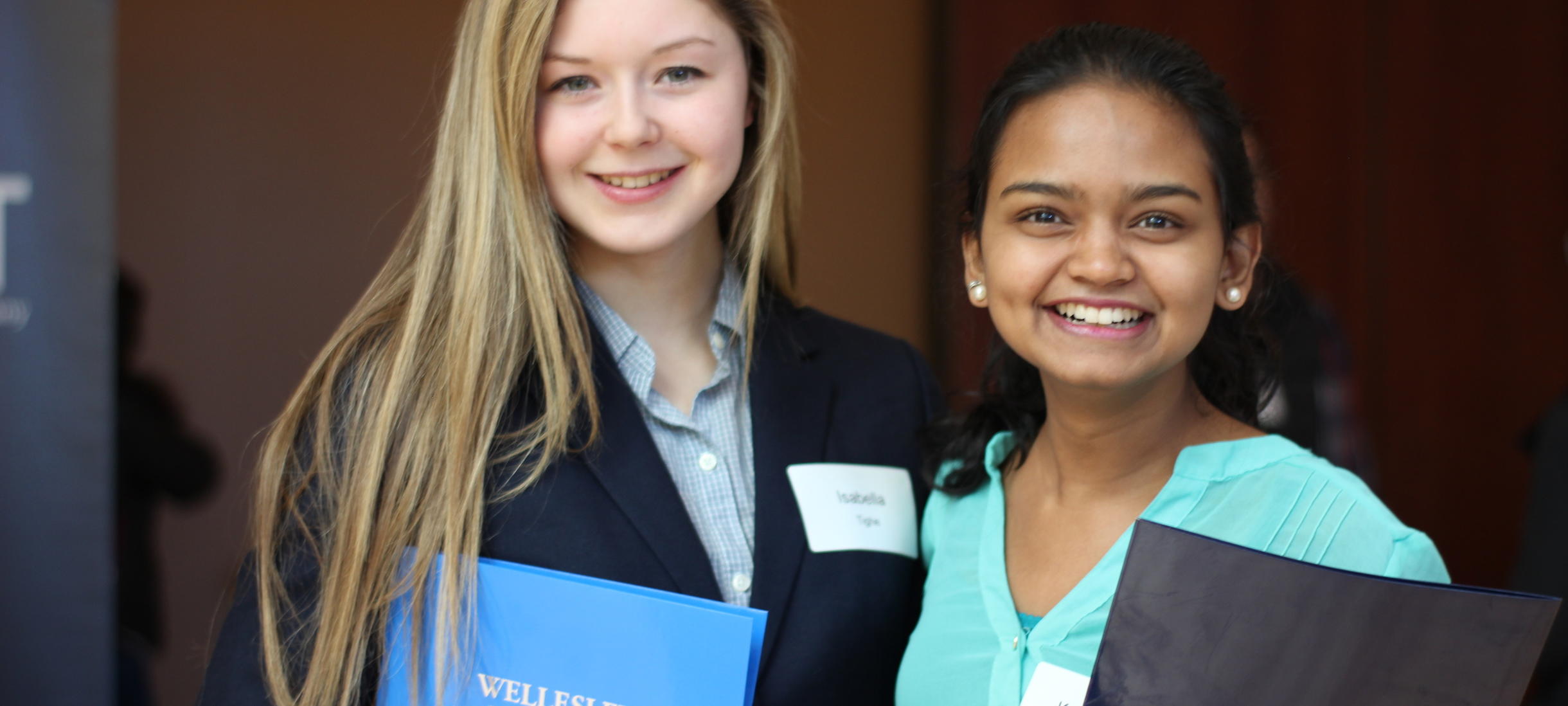 Two students smiling holding Wellesley College folios