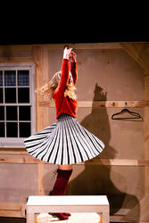 An actor spinning in a circle skirt while on stage.