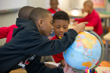 two students study a globe 