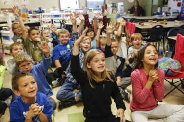 elementary students raise their hands