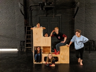 Five students posing on a wooden set piece.