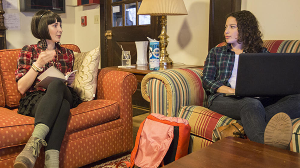 Two students having a conversation in a living room of a dorm.